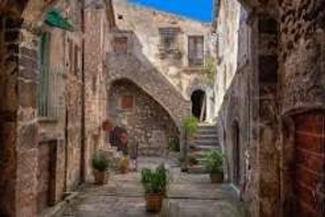 Vicolo in pietra di un borgo italiano, con vasi di piante sulle scale
