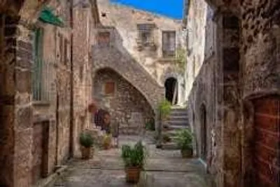 Vicolo in pietra di un borgo italiano, con vasi di piante sulle scale
