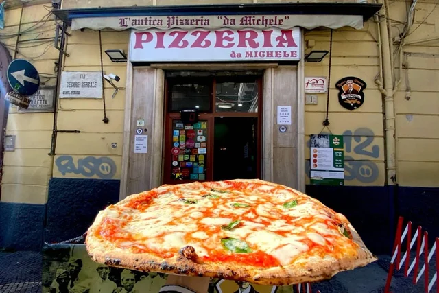 Ingresso storico dell'Antica Pizzeria da Michele in Via Cesare Sersale a Napoli, con una pizza margherita in primo piano